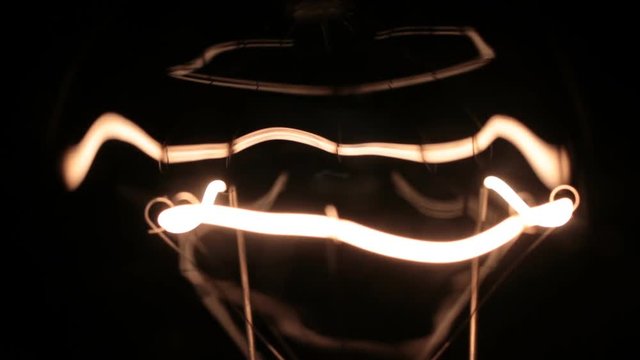 Beautiful reflections and glare of the yellow spiral of the incandescent lamp.