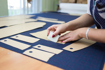 Female seamstress transfering pattern pieces onto fabric. Close up detail of garment production.