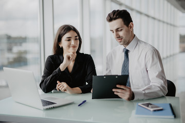 Client signing a document in an office with a businesswoman looking the contract. Office work