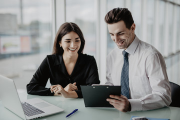 Two entrepreneurs sitting together working in an office desk comparing documents. Office work.