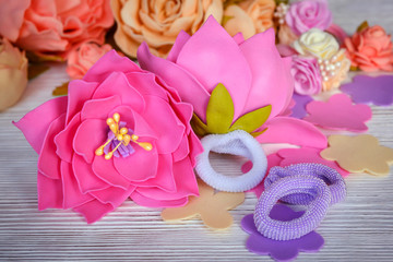 Flowers of FoamIran. Hair ornaments elastic bands on a wooden table. In a retro style.