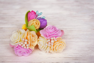 Flowers of FoamIran. Hair ornaments elastic bands on a wooden table. In a retro style.