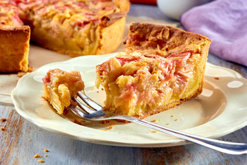 Piece of homemade pie with rhubarb and custard on wooden table