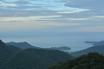 Fototapeta premium Vista de Ubatuba de cima da Serra do Mar, com camadas de montanhas azuis que acabam no mar. 