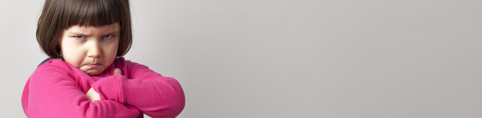 frustrated child sulking with crossed arms and dirty look, banner