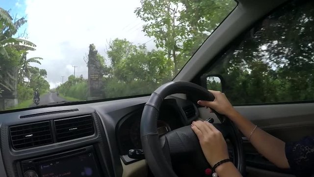 Video footage of young woman hands driving a car on countryside road