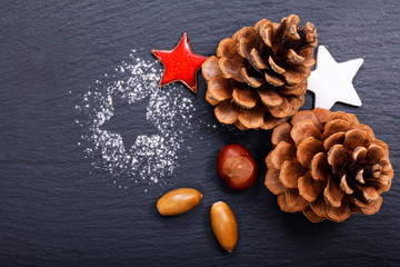 Background Christmas and New year Concept Pine cones and nuts with ceramic decoration  on black slate stone background