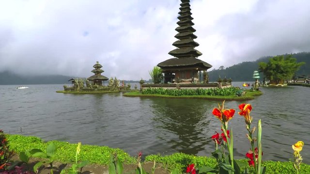 Stunning view footage of Ulun Danu Bratan Temple with flowers and cloudy sky in Tabanan, Bali, Indonesia.