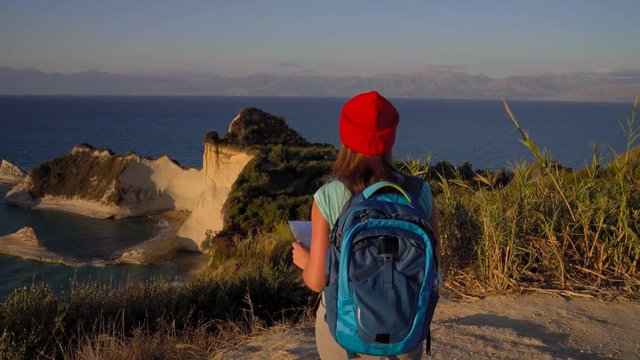 Woman with a backpack and map goes to the Cape Drastis at Corfu island in Greece