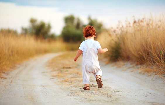 Cute Toddler Baby Boy Running Away Along The Path At Summer Field