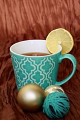 Obraz na płótnie Canvas Vertical image of turquoise pattern mug filled with tea and slice of lemon with background