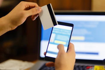 Young man hands holding a credit card and using smart phone for online shopping at home.Online shopping concept.