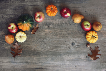 Colorful Fall Thanksgiving Harvest Background with Apples, Pumpkins, Pear Fruit, Leaves, Acorn Squash and Nut Border Over Dark Wood, Shot Directly Above