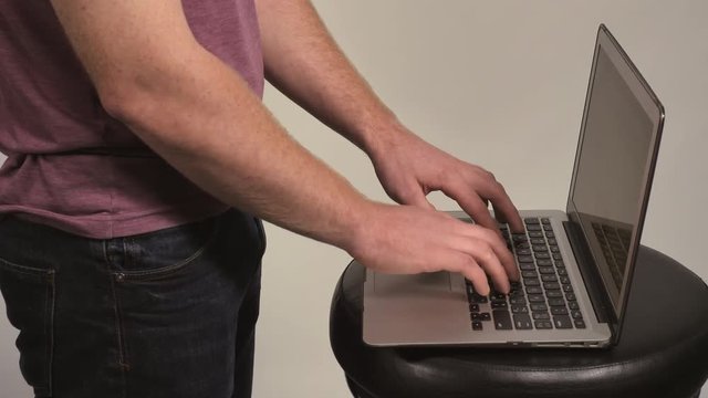 unrecognizable man typing on laptop. Male standing near computer entering data or surfing internet