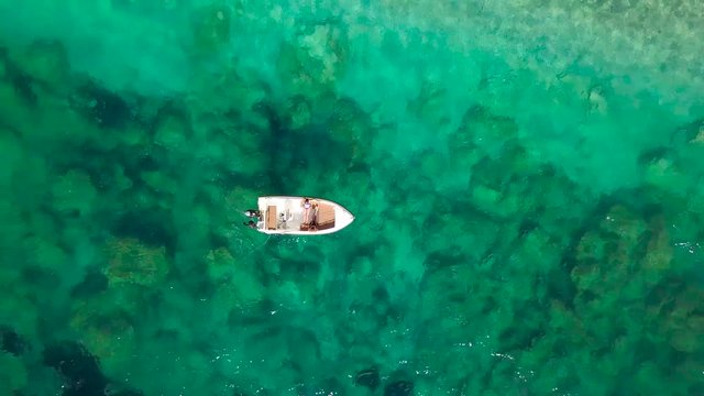 Aerial survey of a couple on a boat sunbathe together on a warm summer day