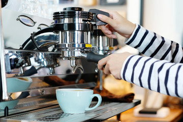 Woman hand using coffee machine at cafe counter, food and drink concept