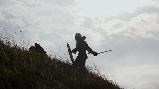 Silhouettes of two warriors Viking are fighting with swords and shields.