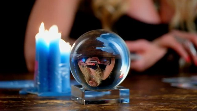 Witch guesses on the cards, sitting at the table, focus to crystal ball