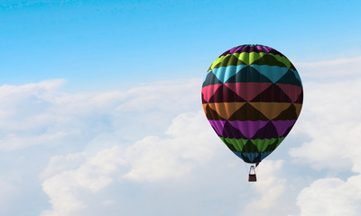 Aerostat floating in day sky. Mixed media