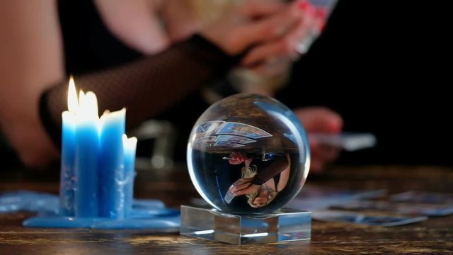 Witch guesses on the cards, sitting at the table, focus to crystal ball