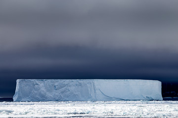 A tabular iceberg with a dark sky backdrop