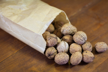 Walnuts sprinkle from a bag on a wooden background