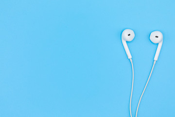 Top view of White Earphones on Blue background. Copy space. Music is my life concept