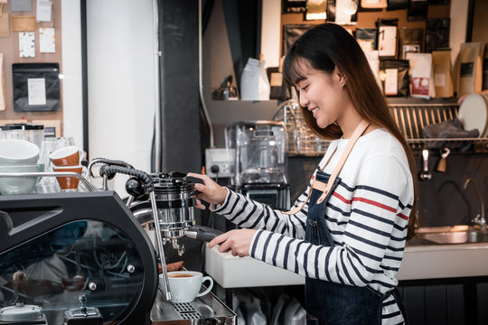 Asia female Barista wear apron making hot coffee menu for customer at counter bar,smiling Owner coffee business concept,food and drink service.