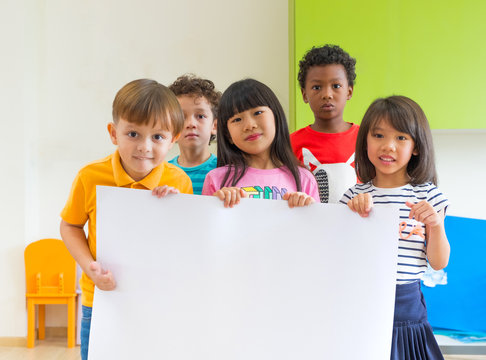Diversity children holding blank poster in classroom at kindergarten preschool,Multiethnic Group with sign board,mock up for adding text or design