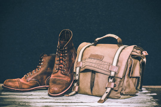 Men's Boots And Brown Bag On Wooden Table 