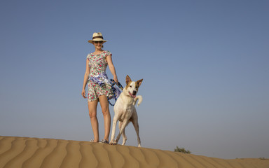 yong woman walking a dog in a desert