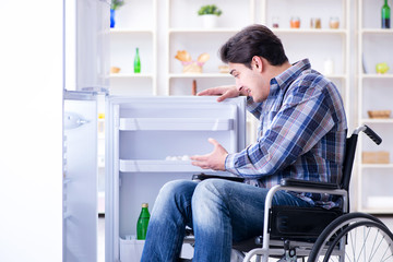 Young disabled injured man opening the fridge door 