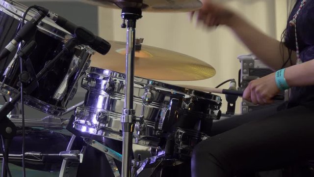 Close up of woman drummer hands playing drums on live concert, side view.
