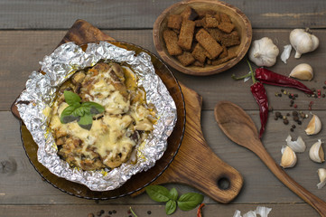 stewed vegetables with meat, mushrooms and cheese on a wooden board. 