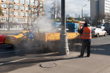 October 2017, Moscow, Russia, street the Warsaw highway. A worker in an orange vest like paper and dirt from roadside poles with a jet of water under pressure