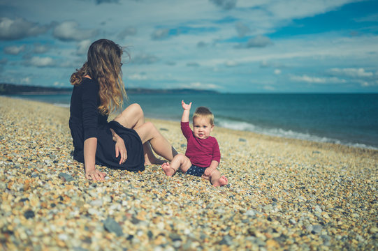 Young mother sitting on beach with her baby