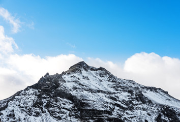 Obraz premium Mountain peak with snow and blue sky with white clouds in winter, winter landscape in Iceland