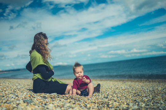 Young mother sitting on beach with her baby