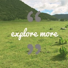 Inspirational motivational travel quote "explore more" on green grass field and mountain background.