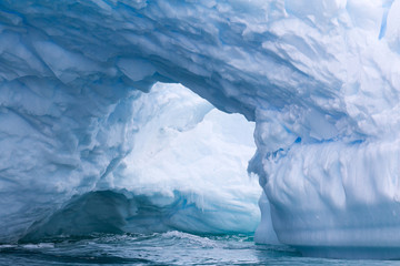 Fototapeta na wymiar A huge cave has been carved in tho this iceberg.