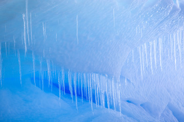 Sunlight only reaches so far in to the iceberg causing blue light to be reflected out.