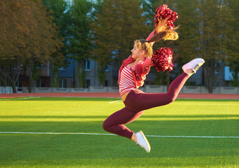 Cheerleading girl on a training jump in the morning at dawn on a field outdoors. Sport, health, fitness