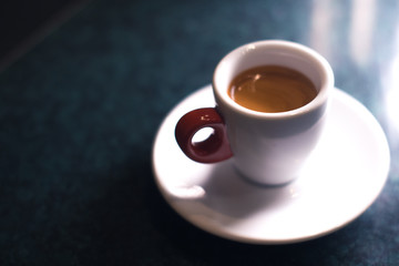 A cup of coffee is americano on a dark background.