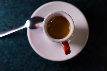 A cup of coffee is americano on a dark background.