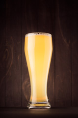 Beer glass with muddy weizen on dark wood board, vertical. Template for advertising, design, branding identity, restaurant menu, cover.