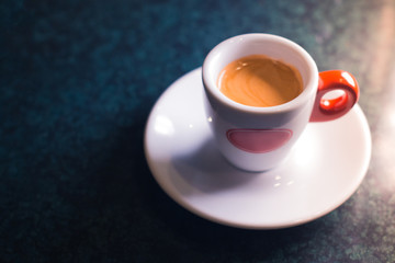 A cup of coffee is americano on a dark background.
