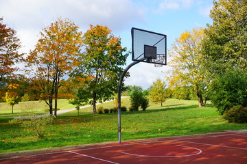 A basketball hoop in a park on a sunny autumn day,

