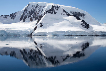 Fototapeta na wymiar A mountain in Antarctica reflects in the water.