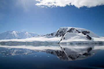 A mountain in Antarctica reflects in the water.