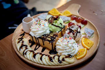 Fruit honey toast. dessert on the wood plate that is Toast and ice-cream top with strawberry and syrup dip